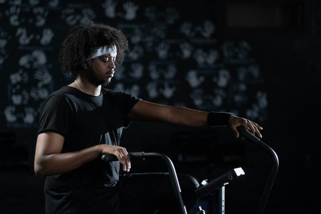 A man in activewear uses a stationary bike indoors, emphasizing fitness and wellness.